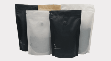 Recyclable coffee stand up pouch with polymer-matched degassing valve and tear notch, beans displayed beside it